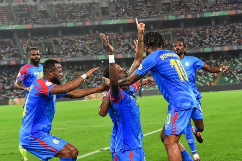 Trophée de la Coupe du monde avec le drapeau de la RD Congo pour illustrer le barrage intercontinental vers le Mondial 2026.