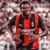Alphadjo Cissé court en souriant sous le maillot rouge et noir de l’AC Milan