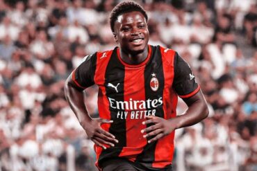 Alphadjo Cissé court en souriant sous le maillot rouge et noir de l’AC Milan