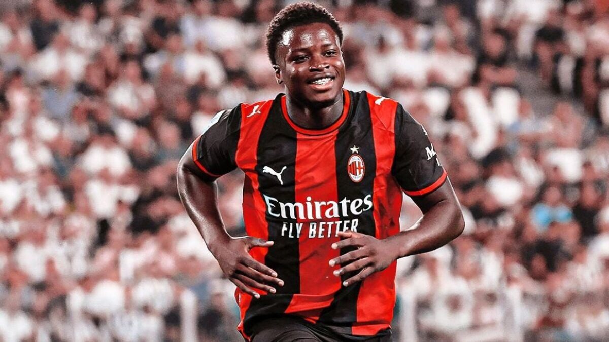 Alphadjo Cissé court en souriant sous le maillot rouge et noir de l’AC Milan